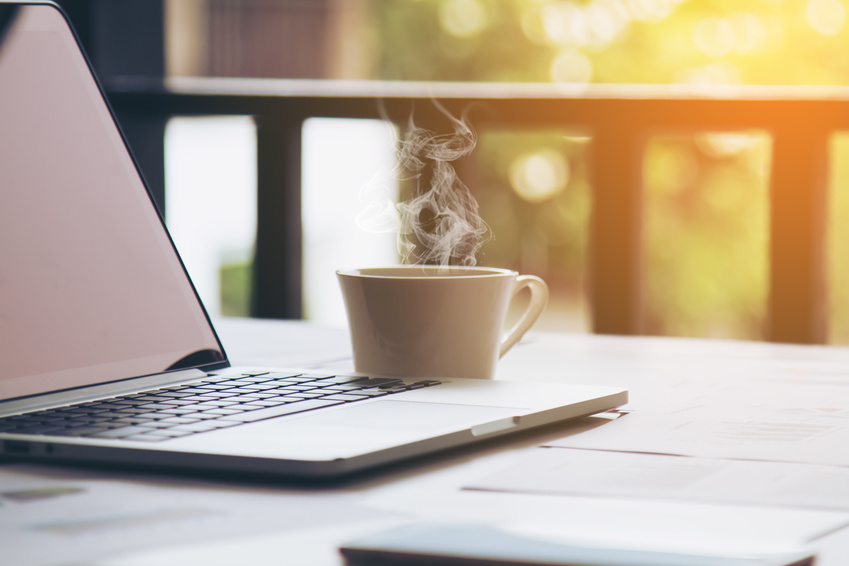Tasse de café fumante à côté d'un ordinateur portable